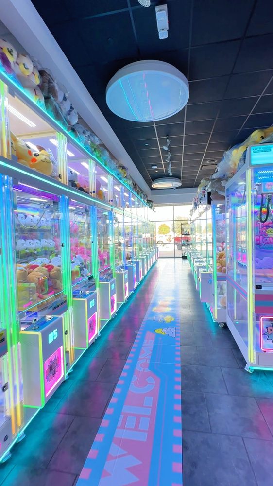 Aisle of glowing claw machines full of plushies inside Claw Zone Hurst